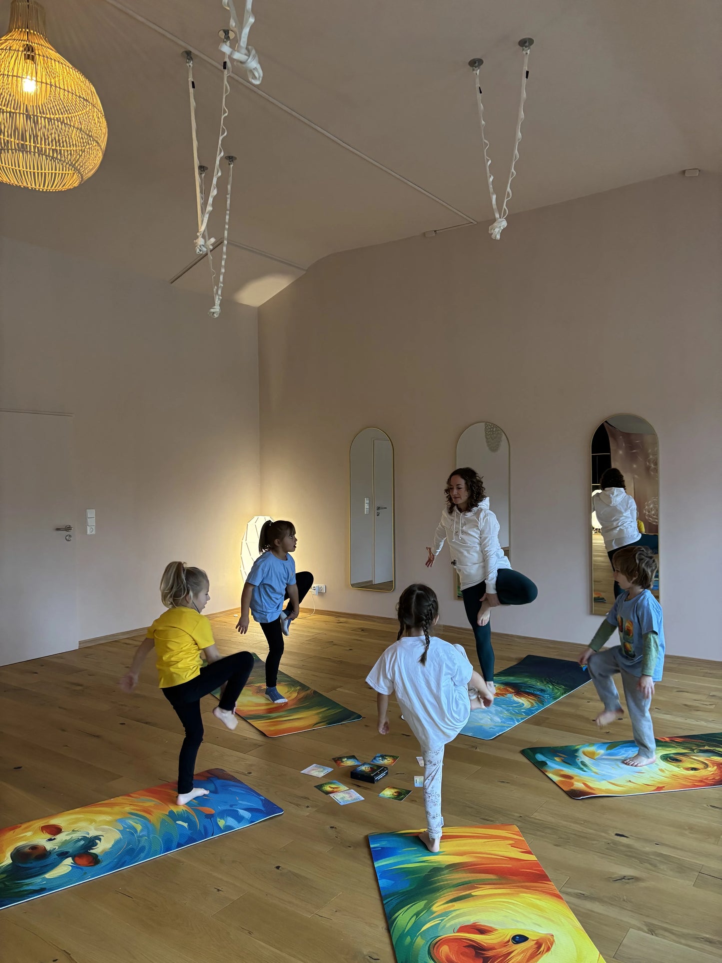 Kinder üben Kinderyoga Baumposition im Kreis auf bunten Kinderyogamatten